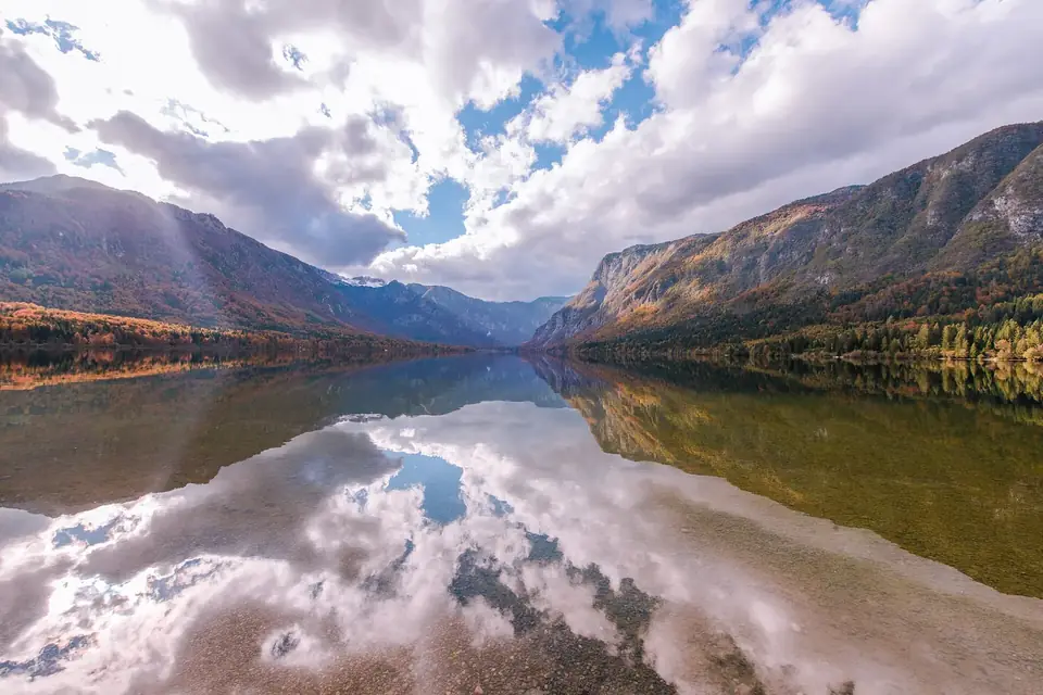 Lago de montanha com nuvens refletidas na água parada